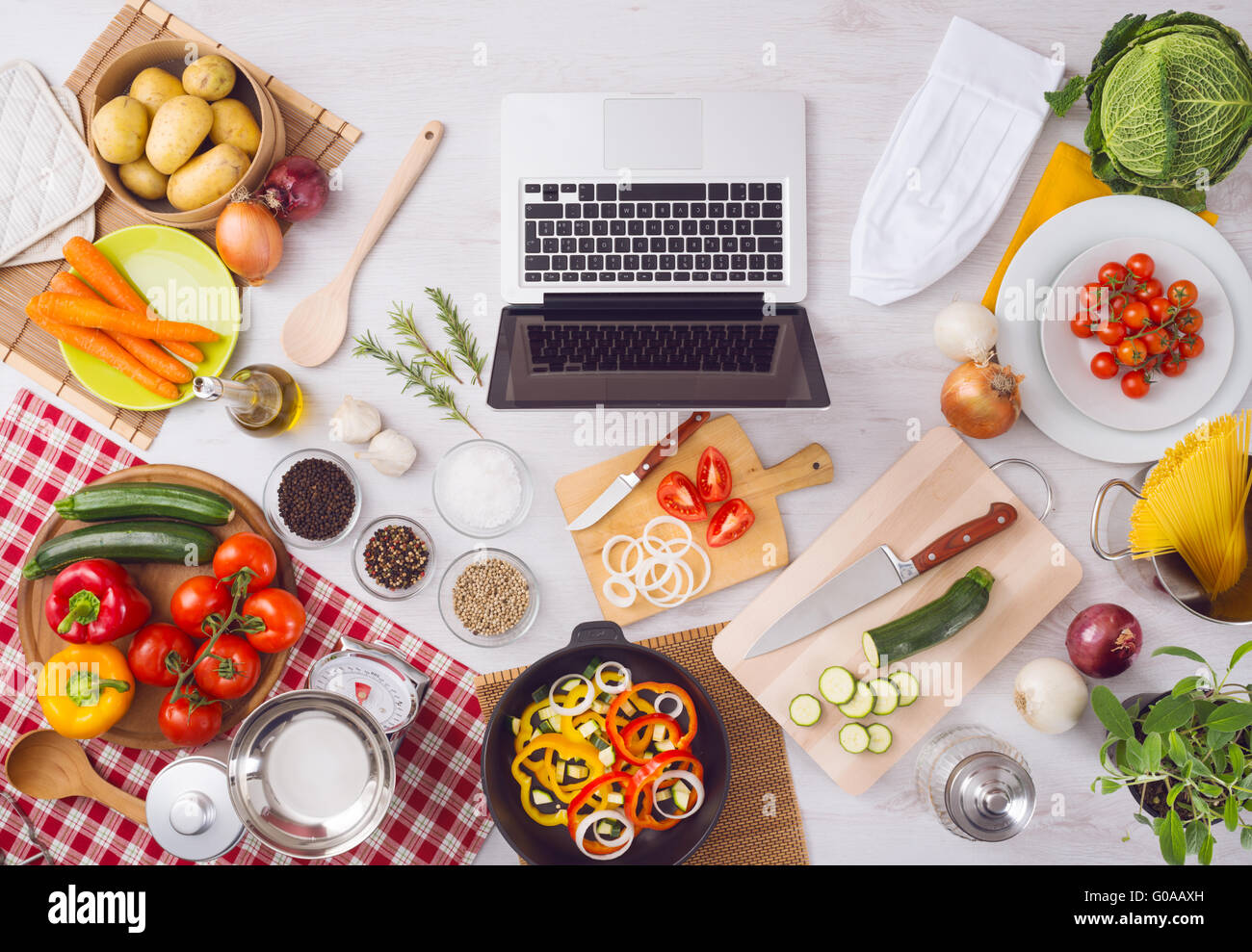 Home kitchen table top view with laptop, food ingredients, raw