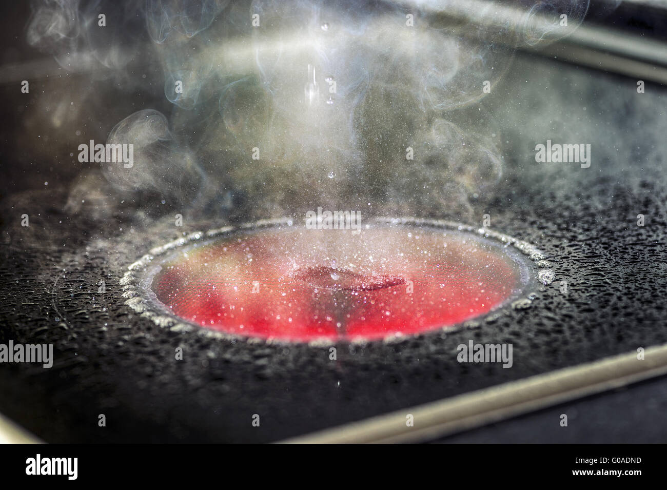 Water droplets evaporate euf a red-hot stove Stock Photo