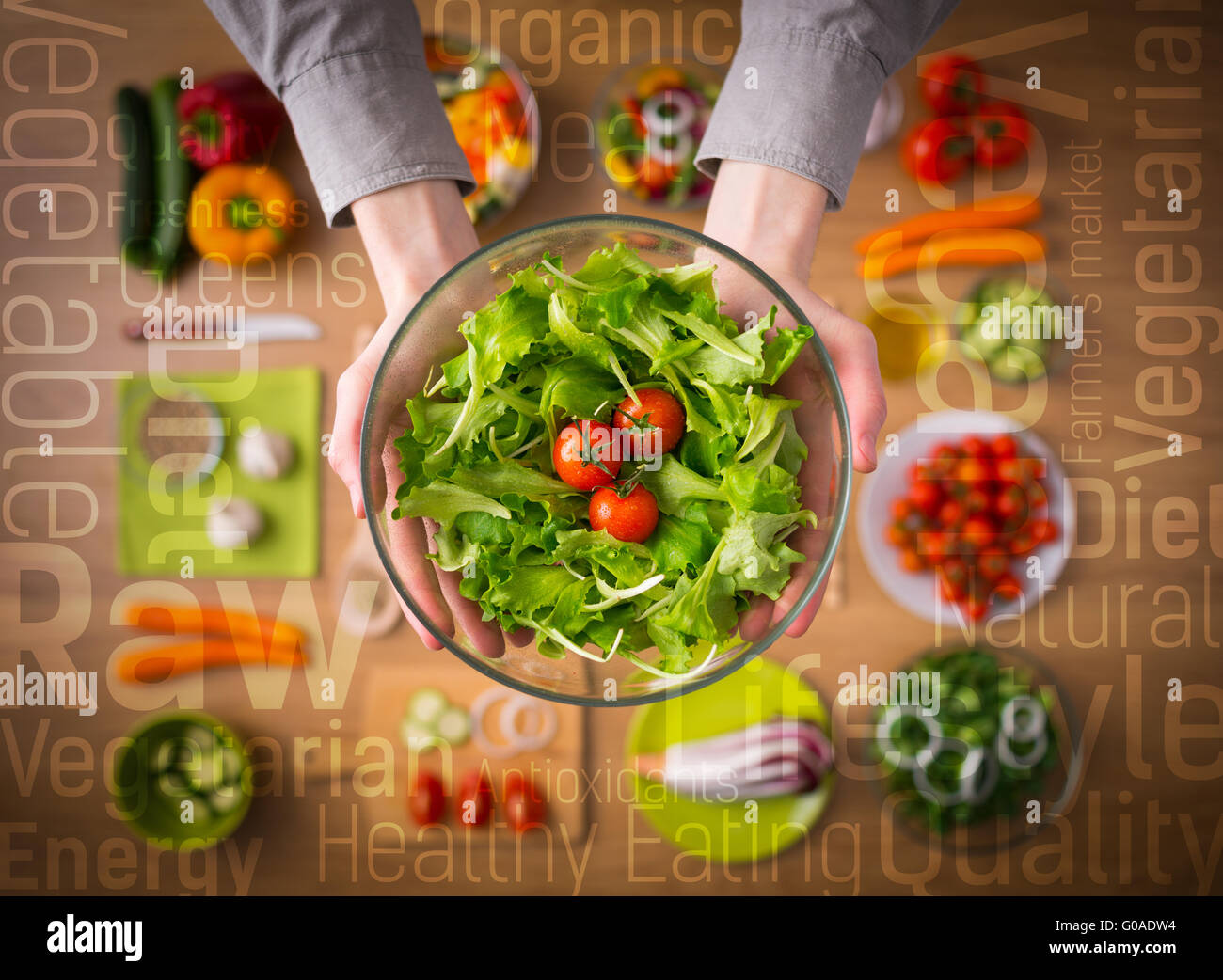 Hands holding an healthy fresh vegetarian salad in a bowl, fresh raw vegetables on background and healthy eating text concepts Stock Photo