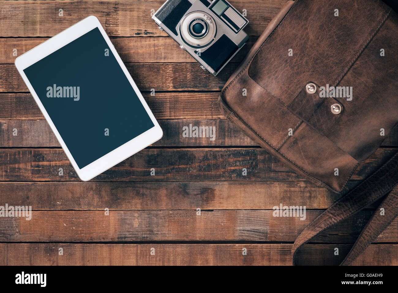 Vintage contemporary traveler and tourist equipment on a table, leather bag, camera and digital tablet, top view Stock Photo