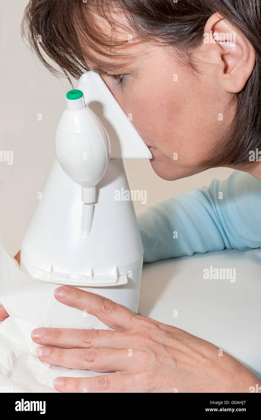 Woman is sitting in front of an inhaler and is inh Stock Photo