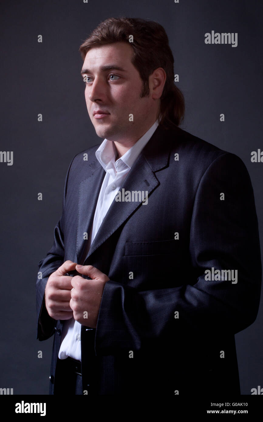 young man in a black suit with a gray background Stock Photo - Alamy