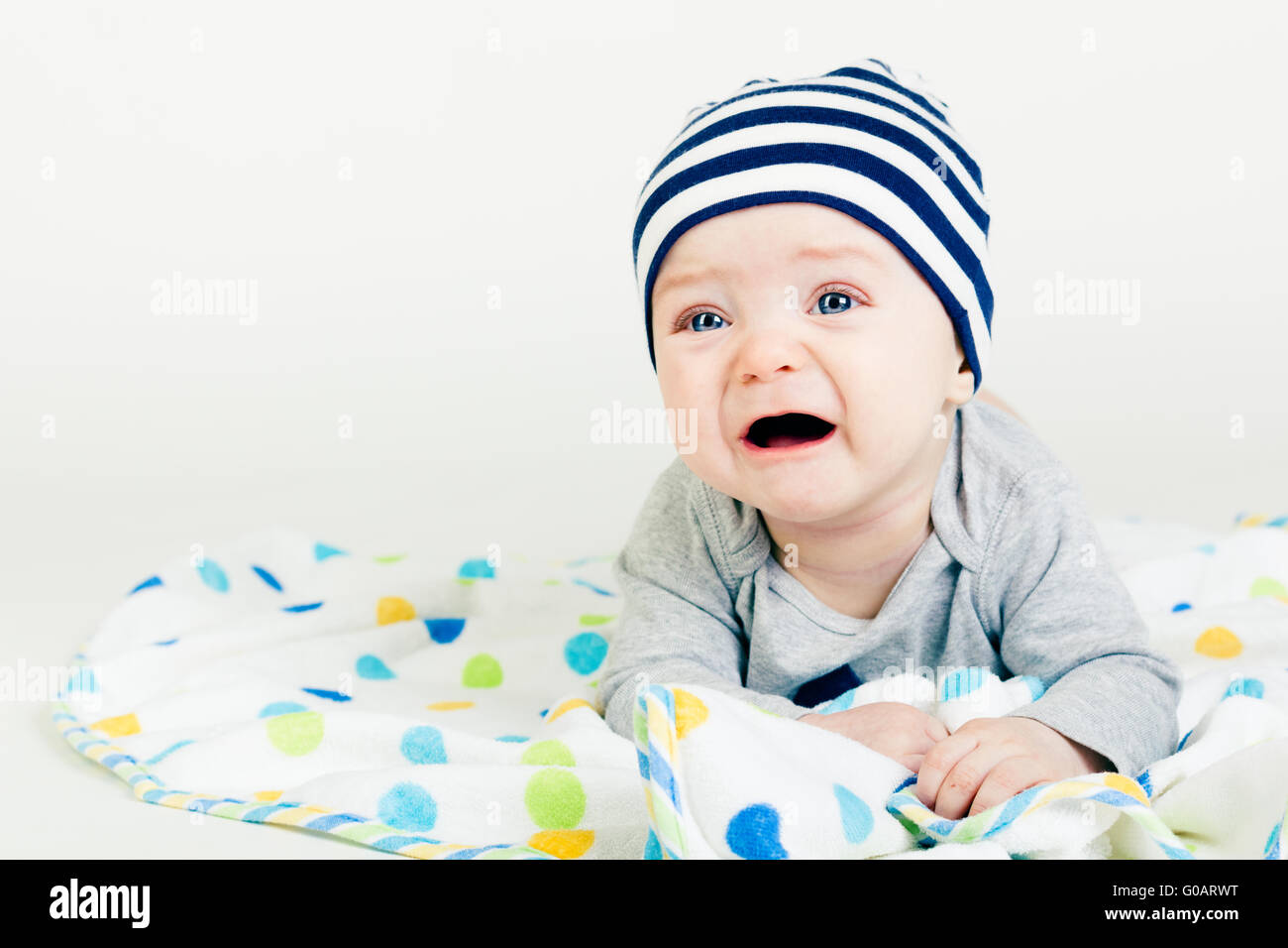 cute baby in striped hat lying down on a blanket Stock Photo