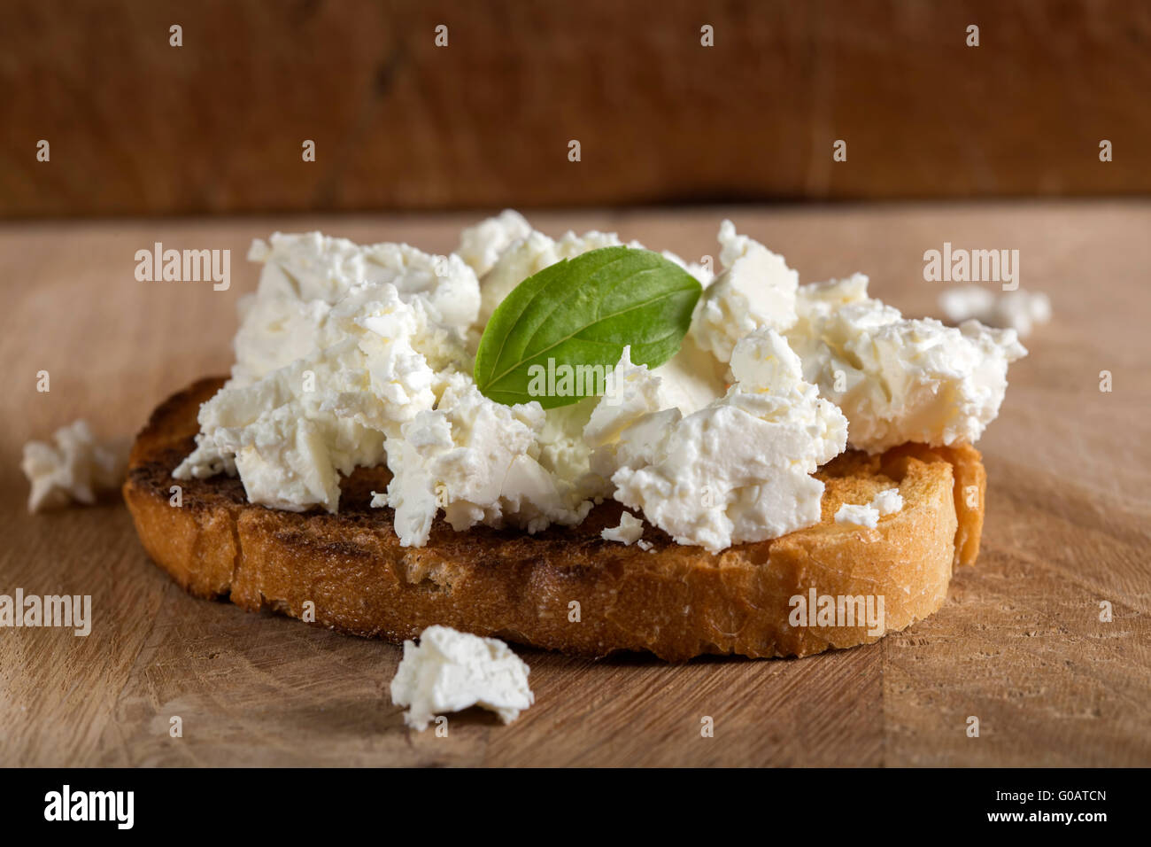 Rye sandwiches or bruschetta with ricotta cheese and basil on wooden board Stock Photo