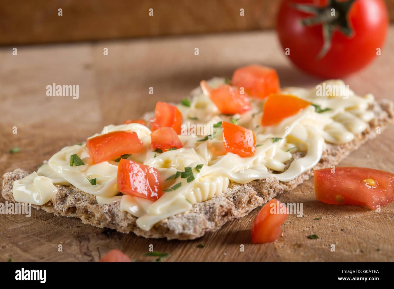 Crispbread with cheese, tomato and herbs on wooden background. Healthy breakfast. Stock Photo