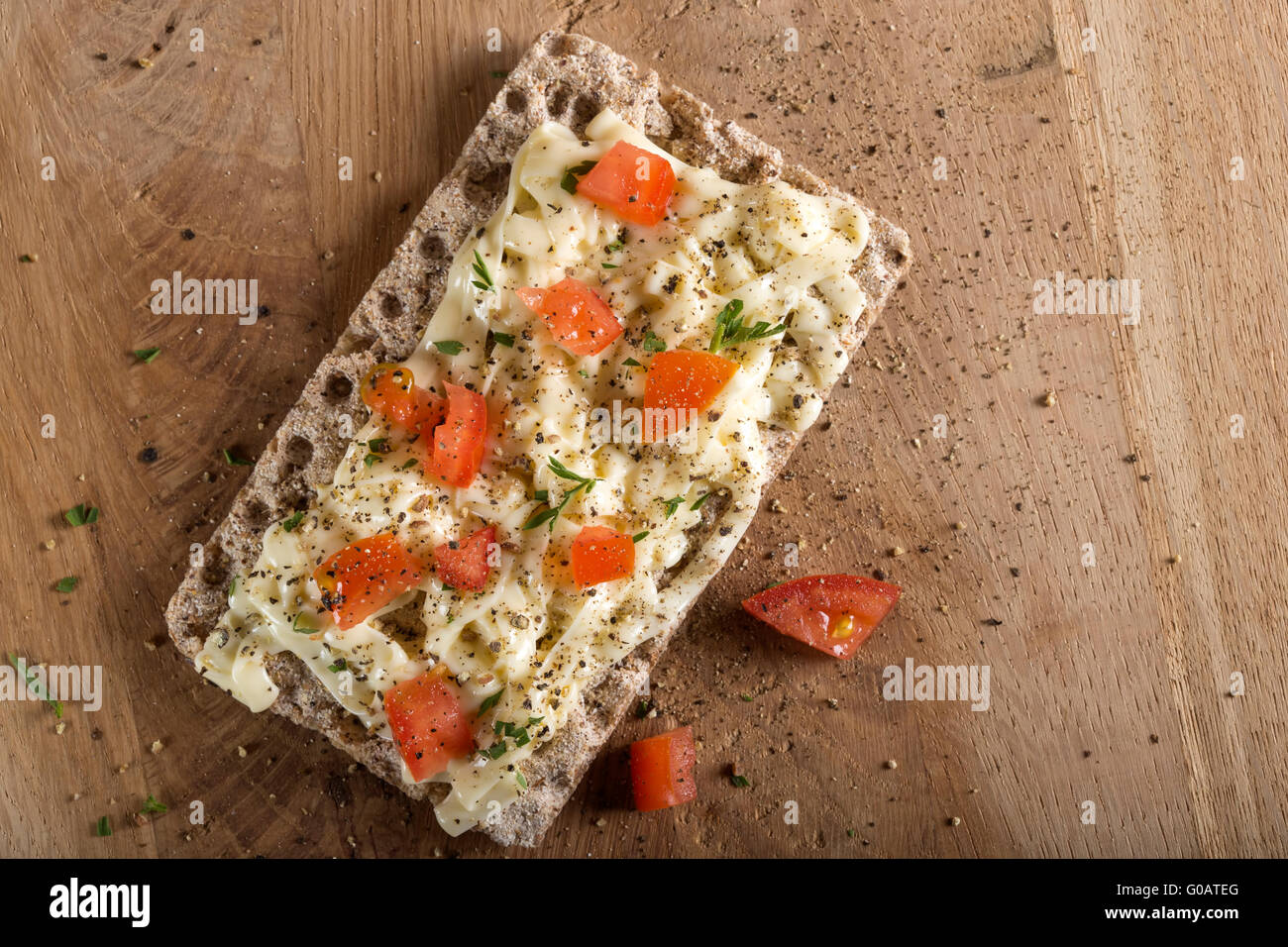 Crispbread with cheese, tomato and spices on wooden background. Healthy breakfast. Stock Photo