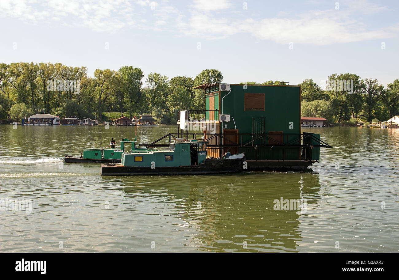 Sava river, Serbia - Two powerboats pushing a raft house against the river currents Stock Photo