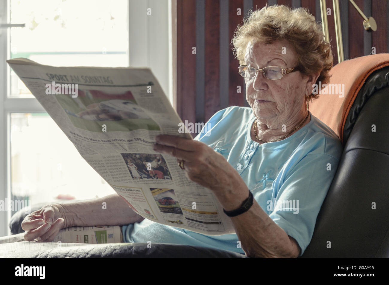 An old lady sitting in her chair by the window, re Stock Photo