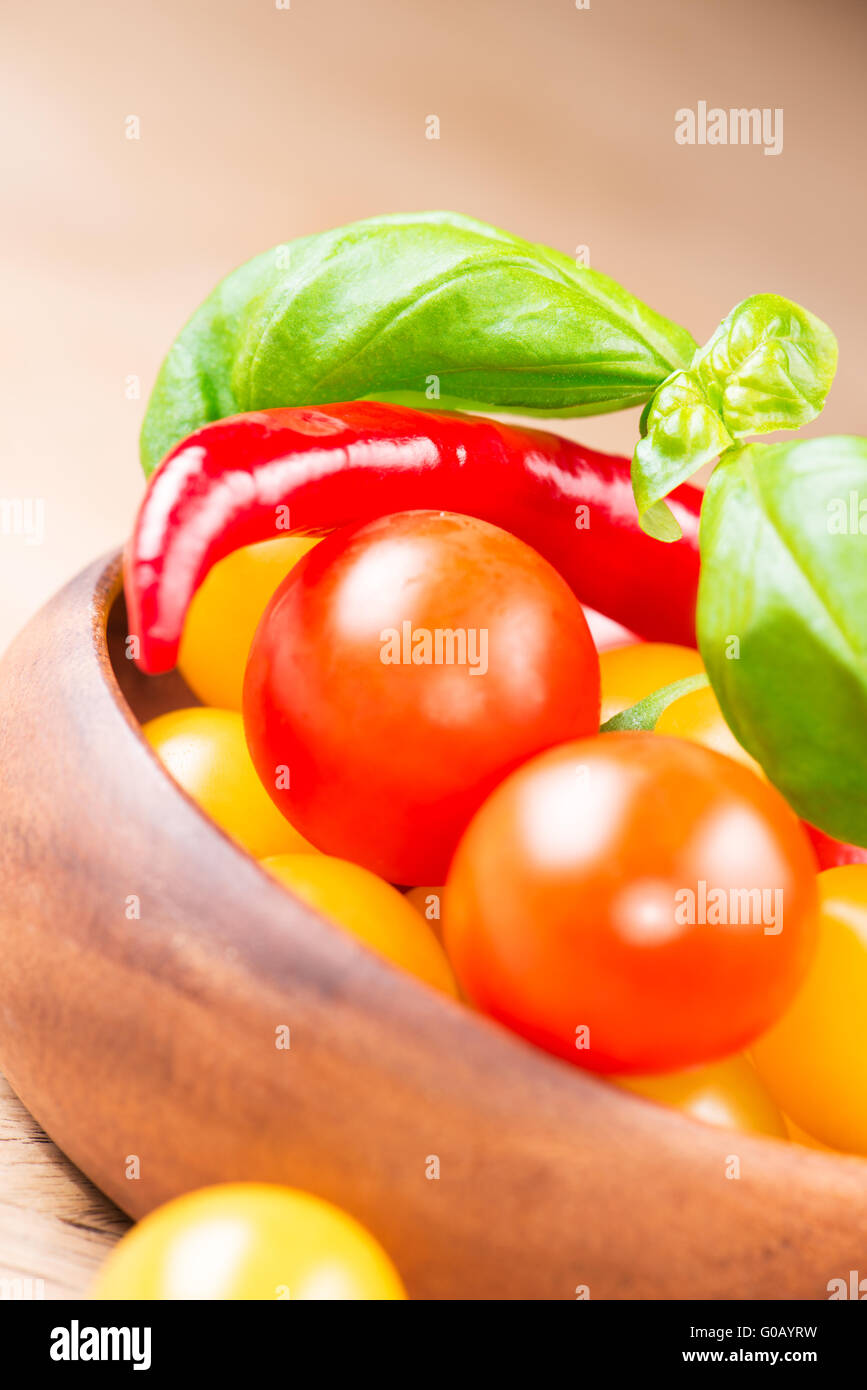 basil with cherry tomatoes and chili pepper in wooden bowl Stock Photo