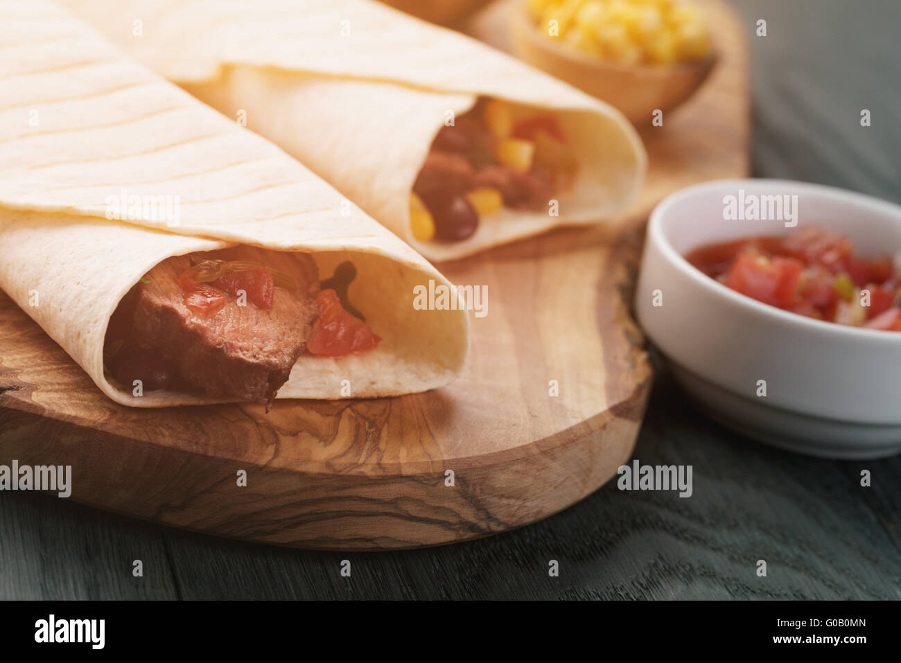 burritos with beef steak, corn, black beans and salsa sauce on wood