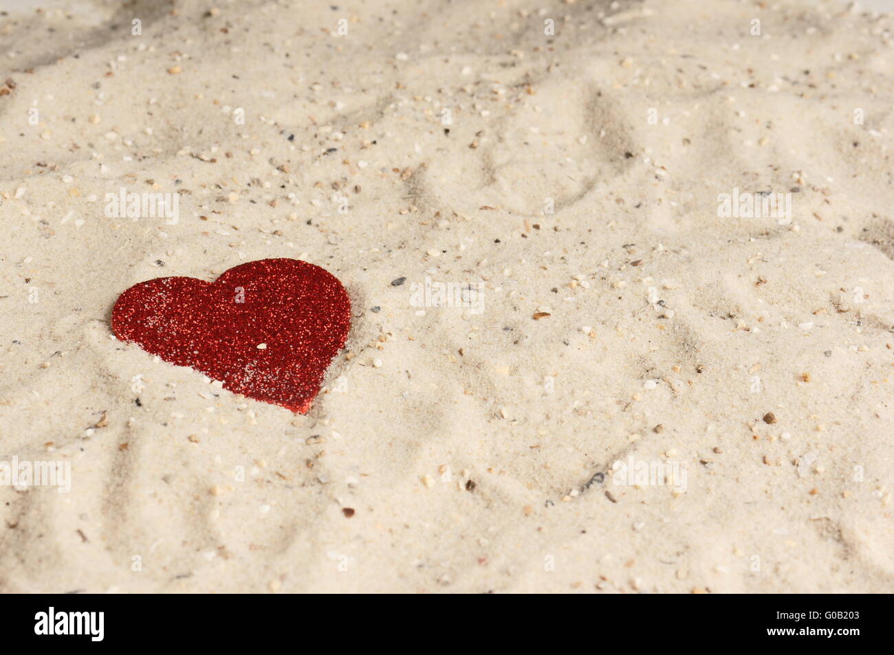 Red heart lying in the sand Stock Photo