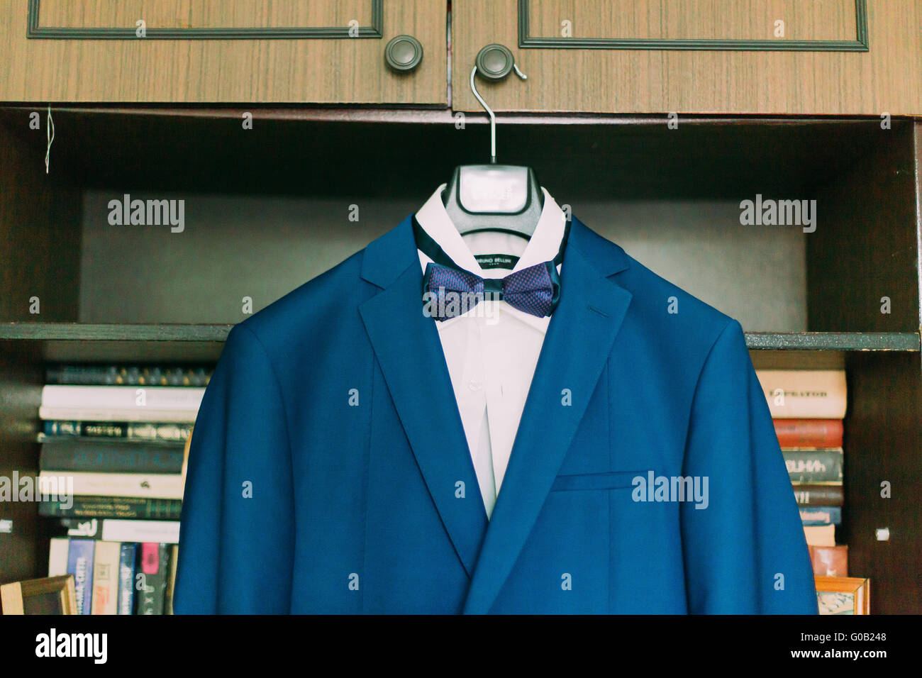 Close-up photo of excellent expensive wedding suit with white shirt and bow-tie hanging in the interior Stock Photo