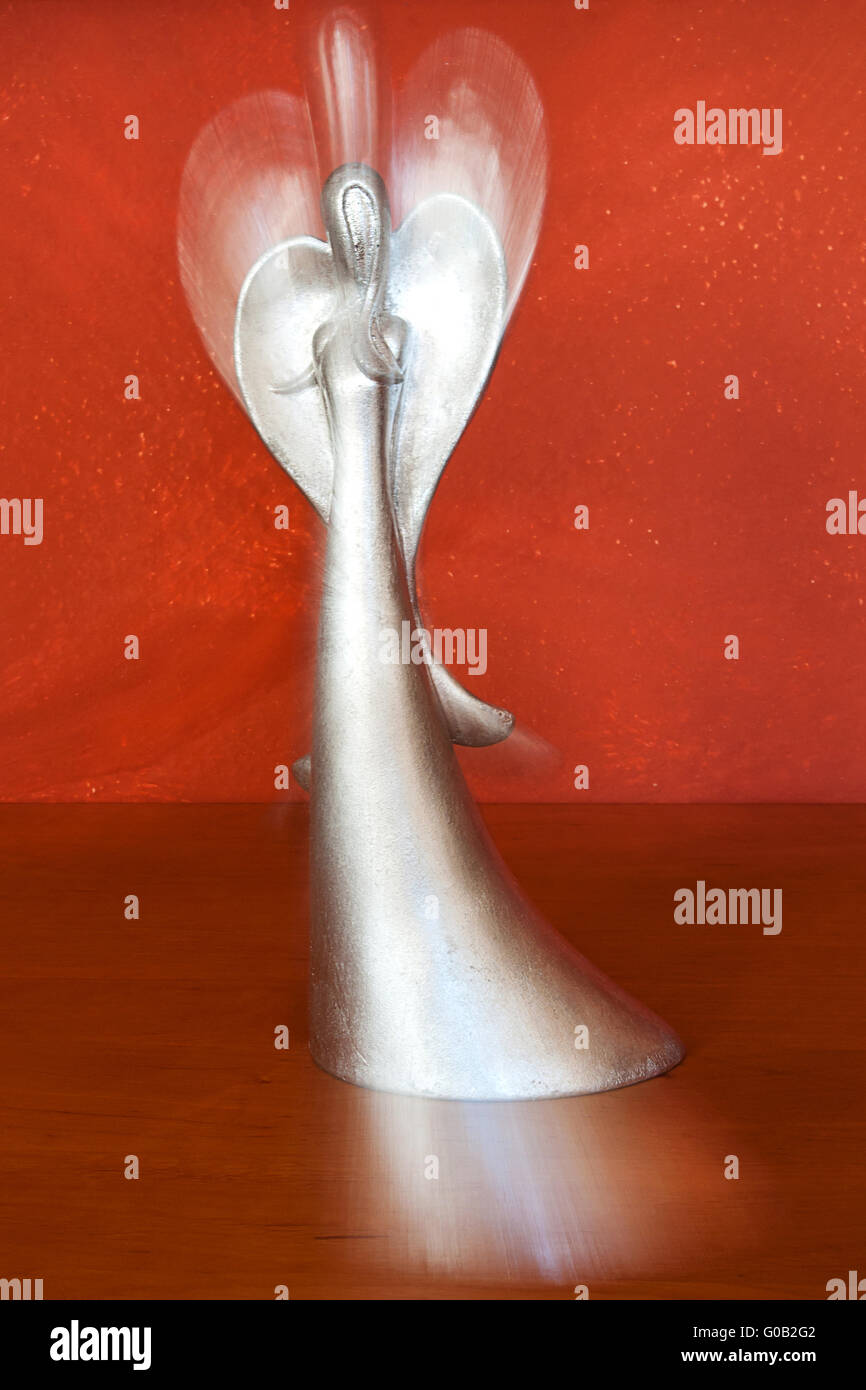 silver angel figure in front of terracotta colored Stock Photo