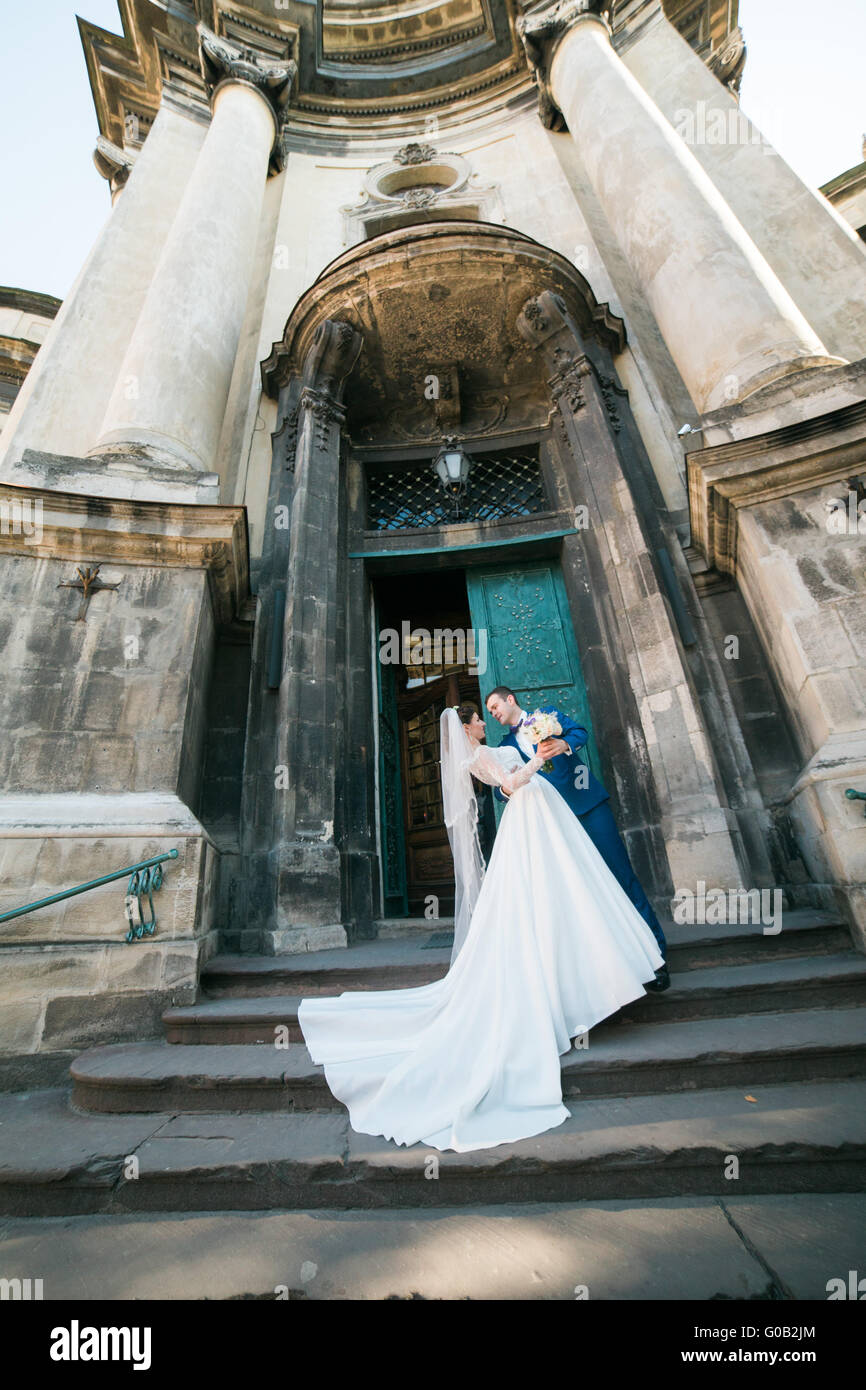 Romantic elegant newlywed couple posing near baroque column church ...