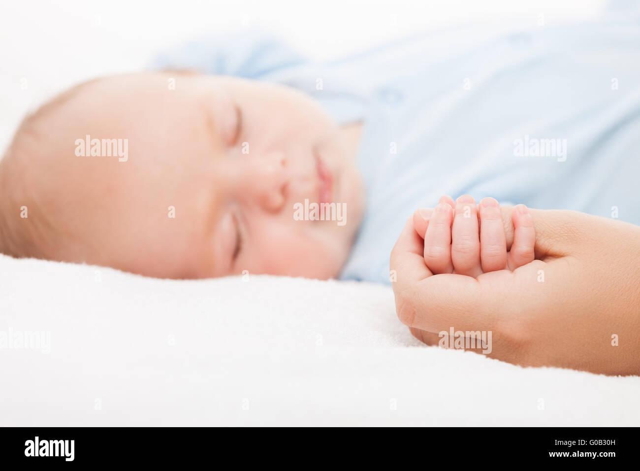 Cute sleeping newborn baby child holding mother ha Stock Photo