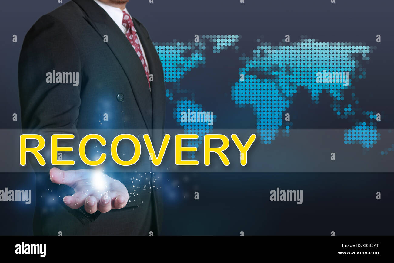 Business concept image of a businessman showing Recovery word on his hand over blue background with dotted world map Stock Photo