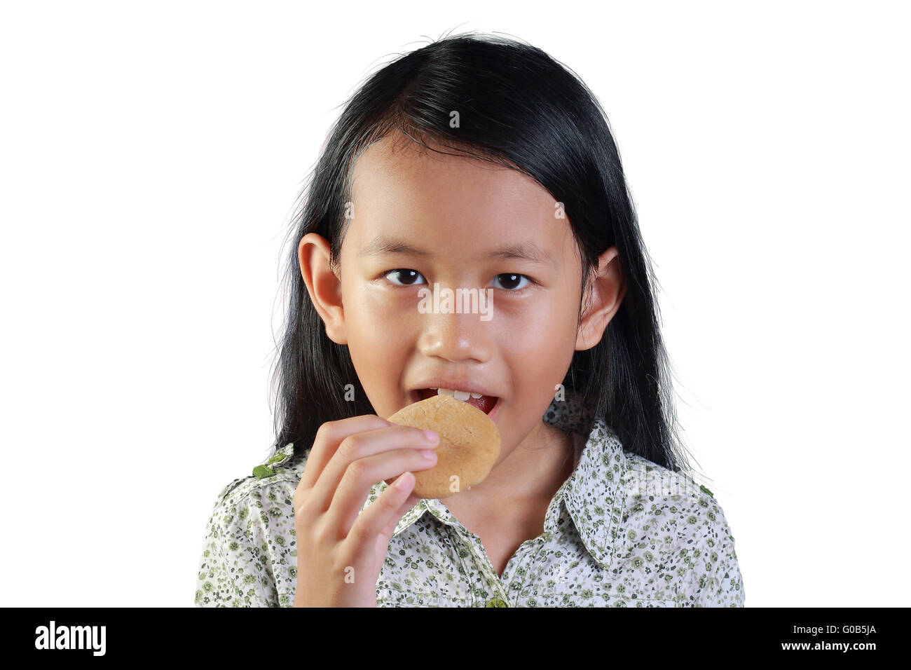 portrait of a happy little Asian girl smiling while eating biscuit isolated on white Stock Photo