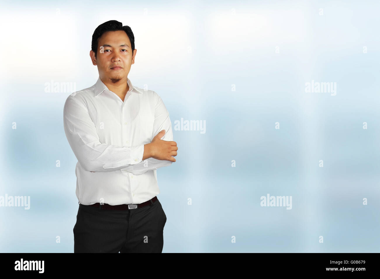 Young Asian male smiling and standing proudly with his hands on the front his chest over bright background Stock Photo