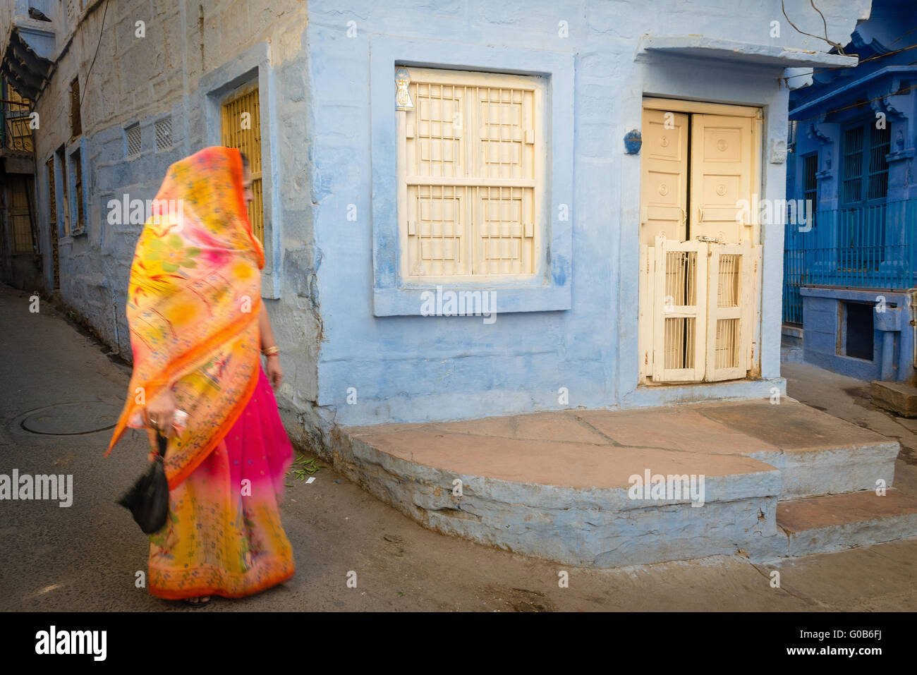 Woman in colourful sari walking past blue house in Jodhpur Stock Photo ...