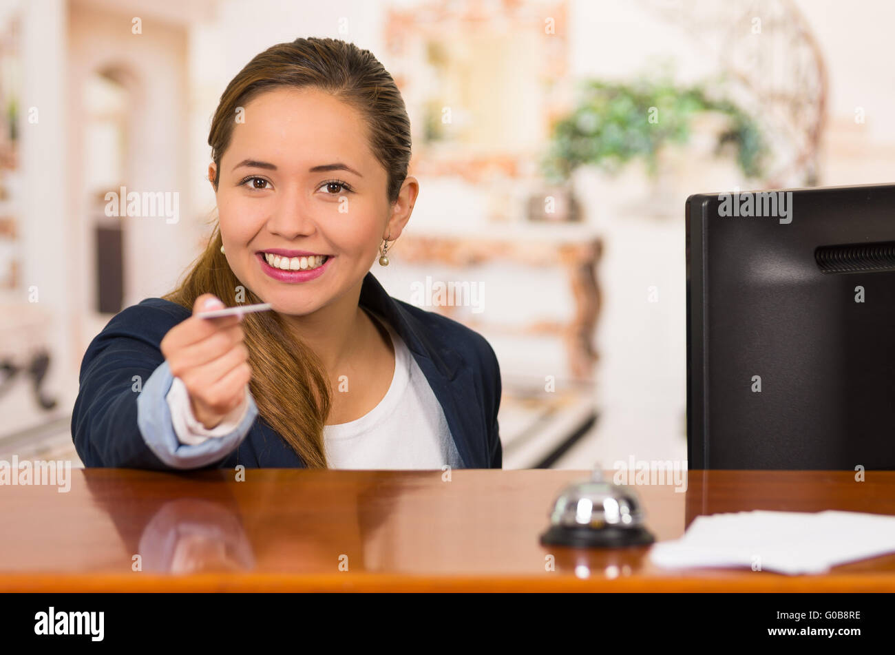 Young hotel receptionist with friendly smile handing over key