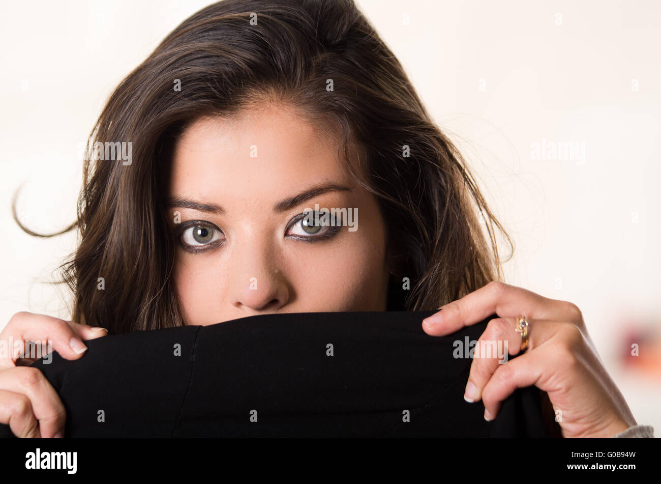 Headshot attractive brunette facing camera covering half her face with ...