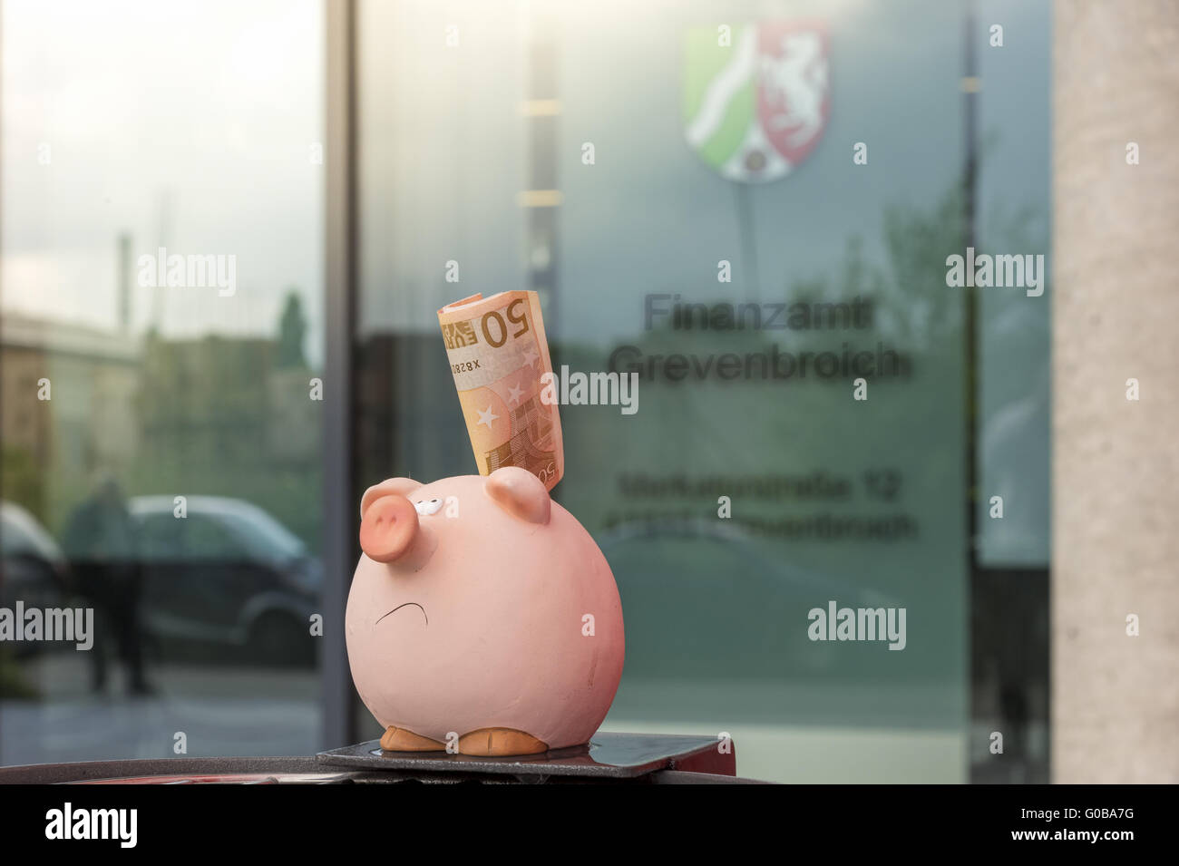 A piggy bank stands with 50 euros before tax offic Stock Photo