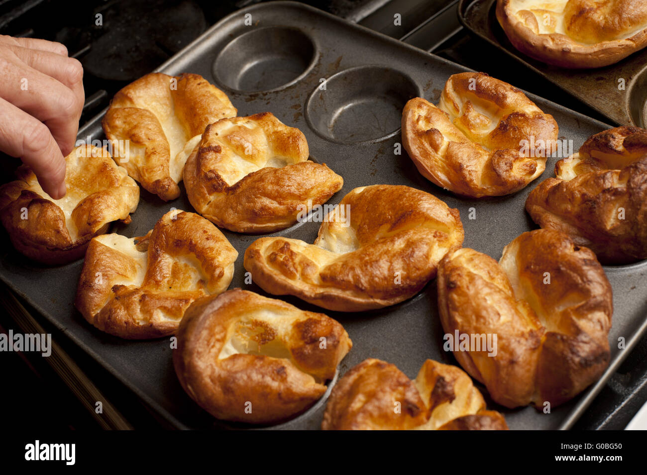 Man removing Yorkshire puddings from a baking tray Stock Photo