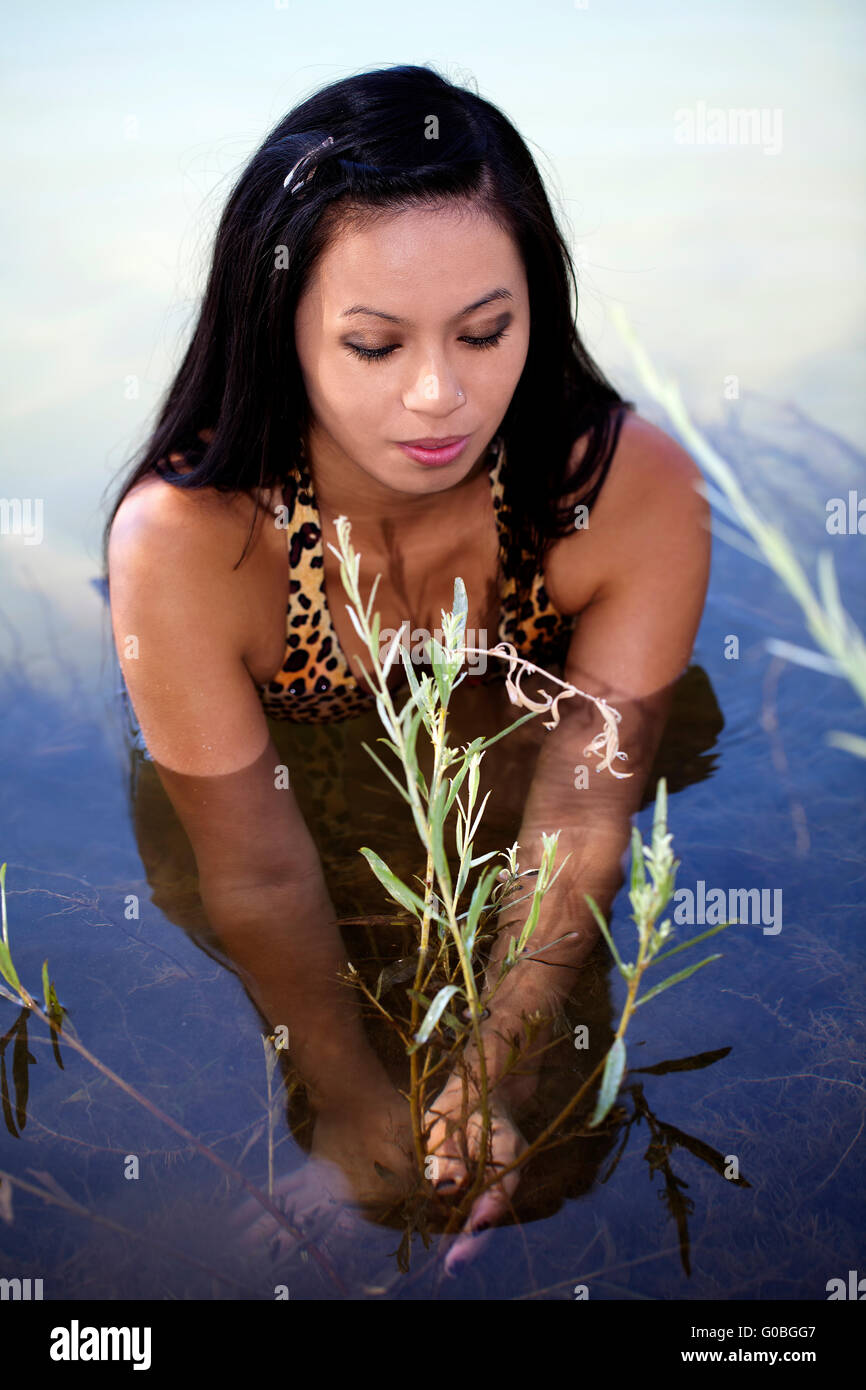 Skinny Oriental Woman Sitting In River Plants Stock Photo