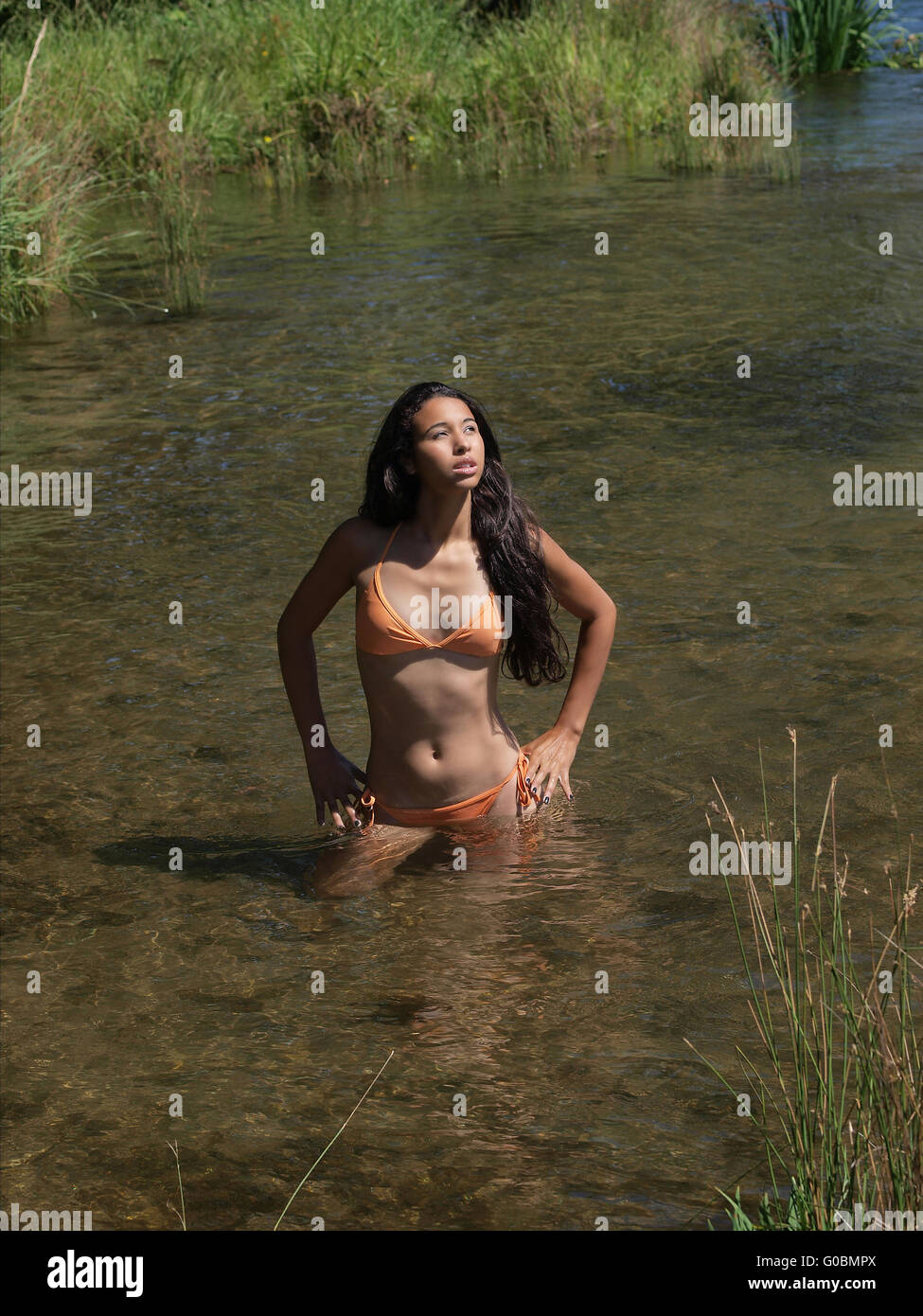 Young mixed woman orange bikini in river Stock Photo