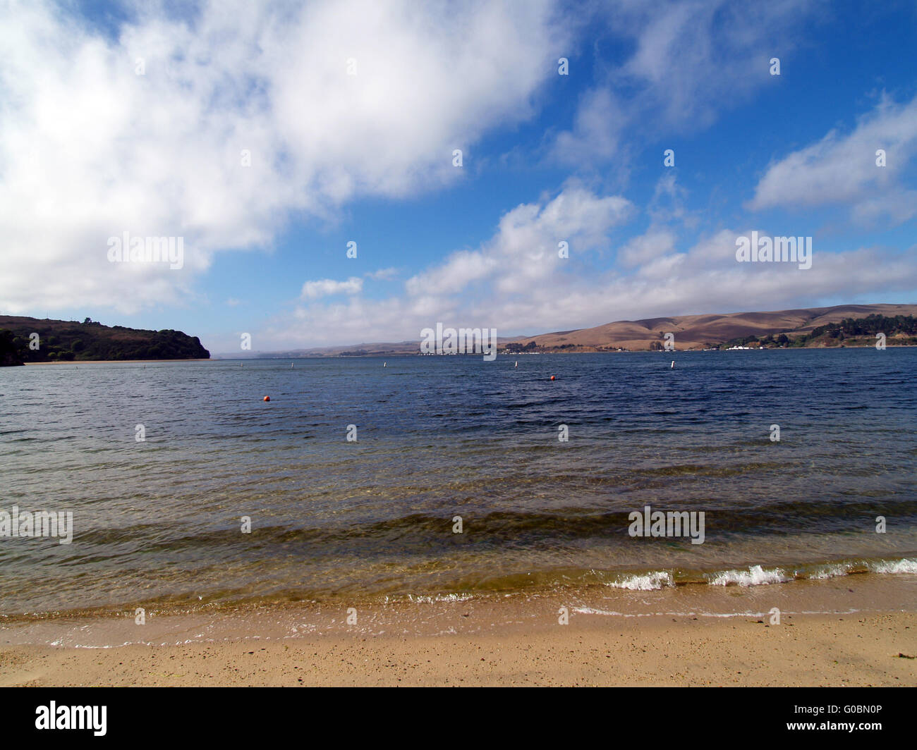 Water beach blue sky and white clouds small waves Stock Photo - Alamy
