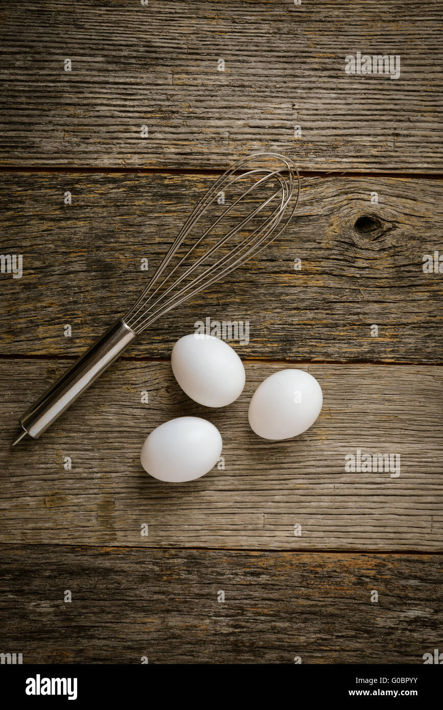 https://c8.alamy.com/comp/G0BPYY/three-eggs-and-whisk-or-egg-beater-on-rustic-wood-background-G0BPYY.jpg