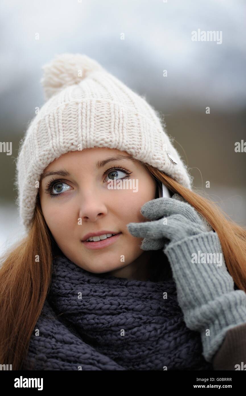 Young female with mobile wearing winter clothings Stock Photo