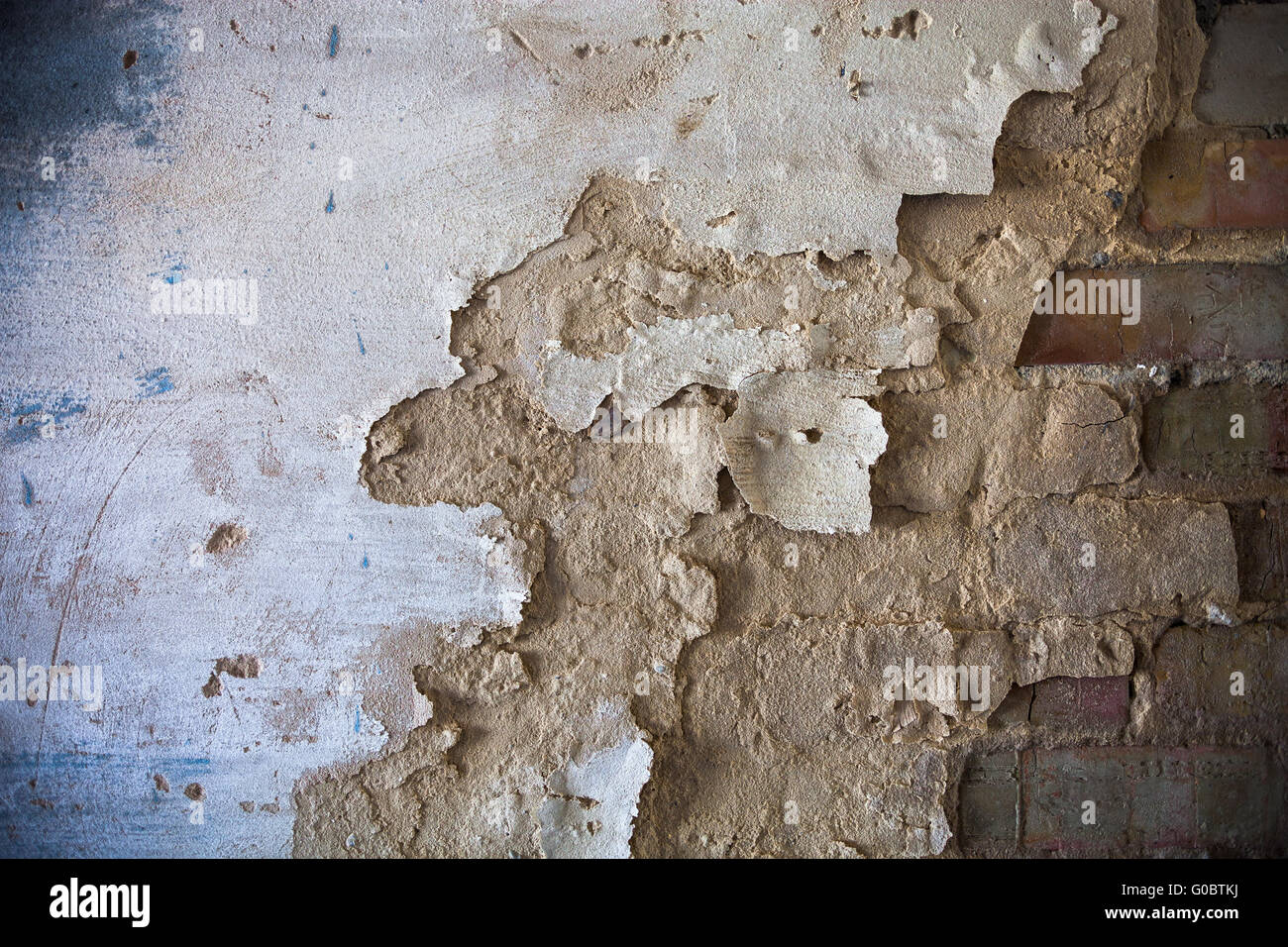 Damaged whitewashed plaster on the brick wall Stock Photo