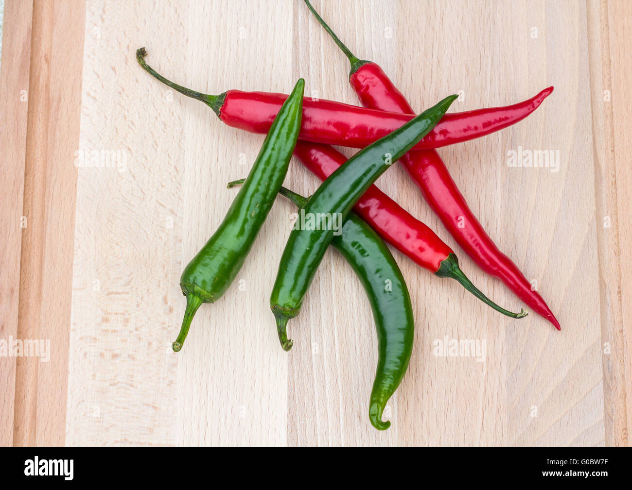 red and green chilli peppers on a chopping wooden board Stock Photo - Alamy