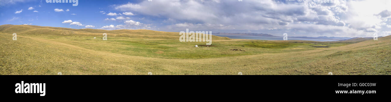 Scenic panorama of green grasslands in Kyrgyzstan with traditional namodic yurt Stock Photo