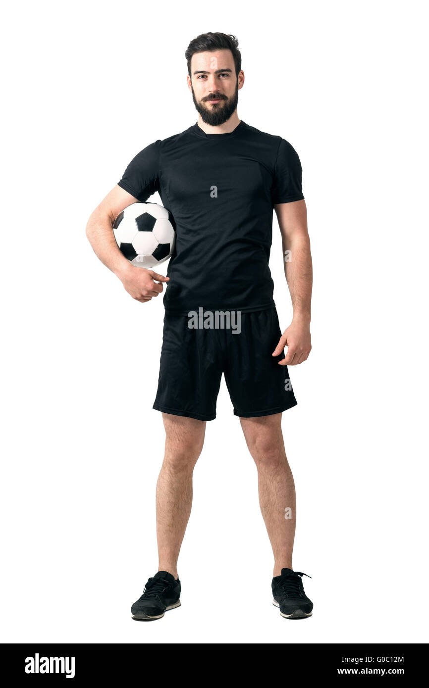 Smiling soccer player holding ball under his arm looking at camera