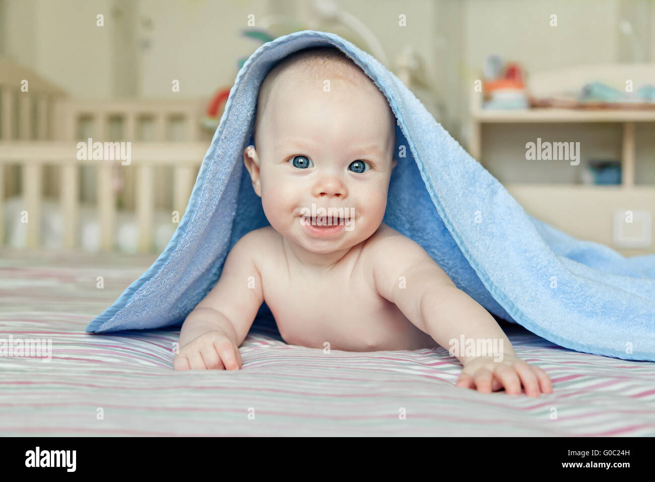 Portrait of a smiling baby with blue towel on his head Stock Photo