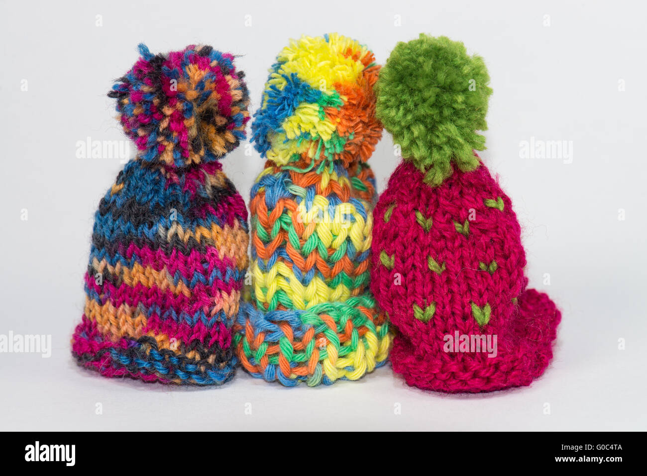 Three little knitted bobble caps Stock Photo