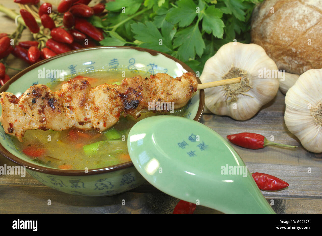 Poultry consomme with chicken skewers and parsley Stock Photo Alamy