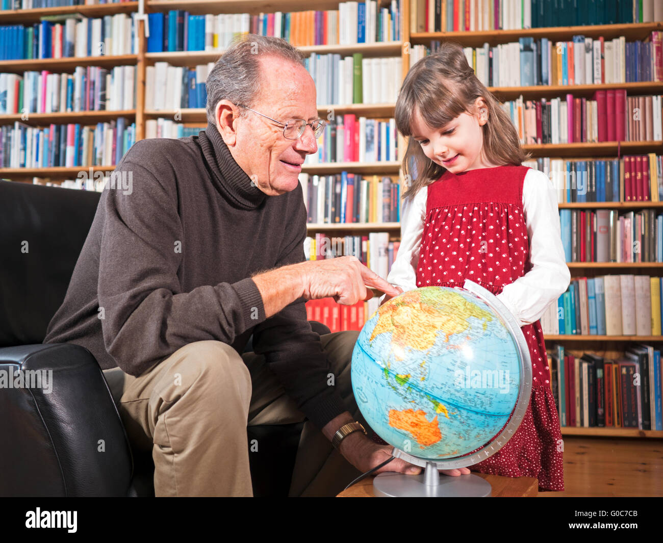 Grandfather and granddaughter looking at a globe Stock Photo