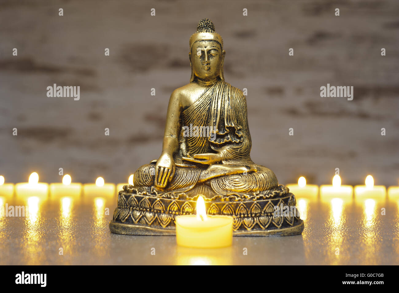 Buddha sitting in meditation with line of candle Stock Photo