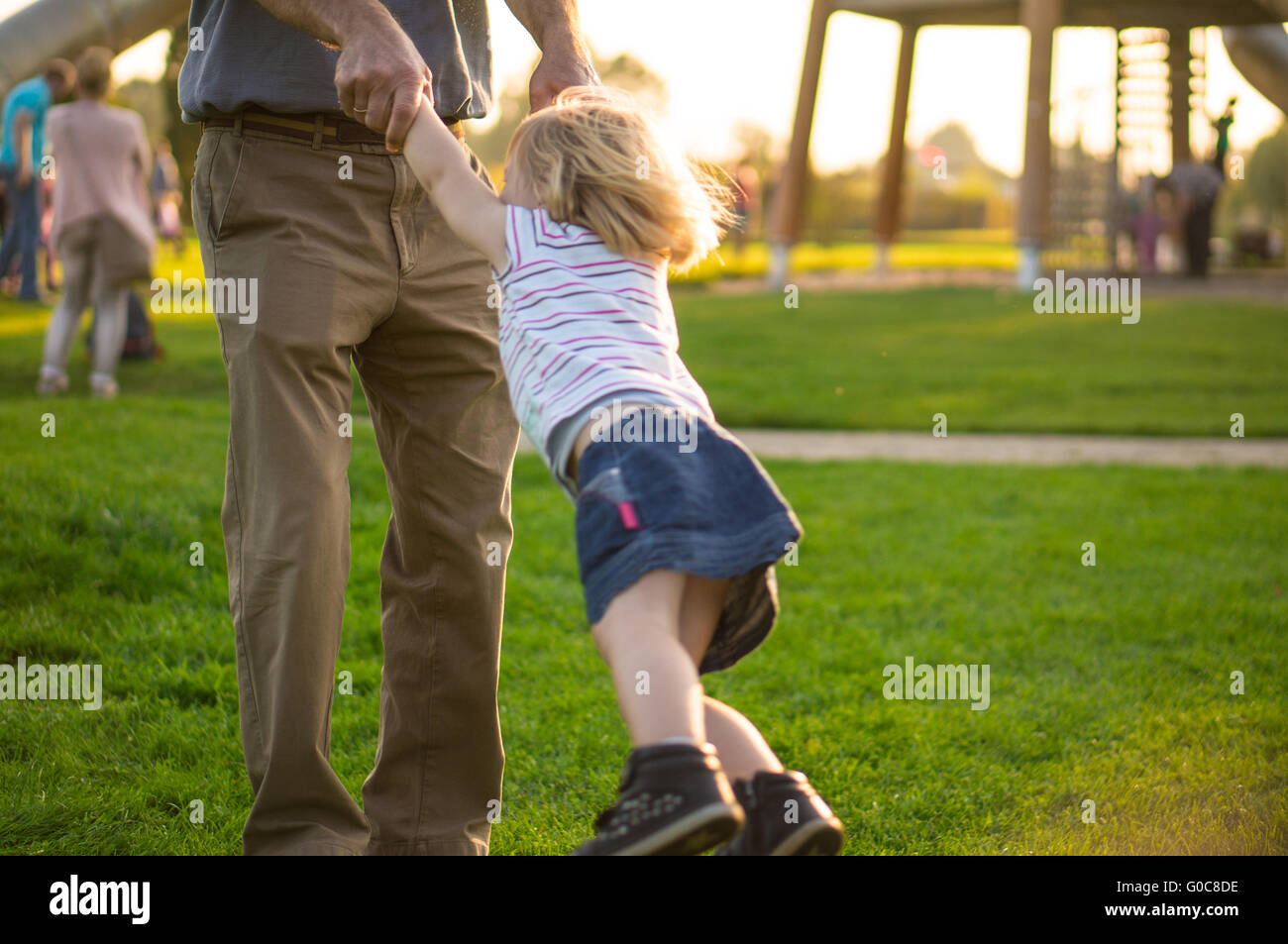 Dad turns her daughter around himself at arm's len Stock Photo
