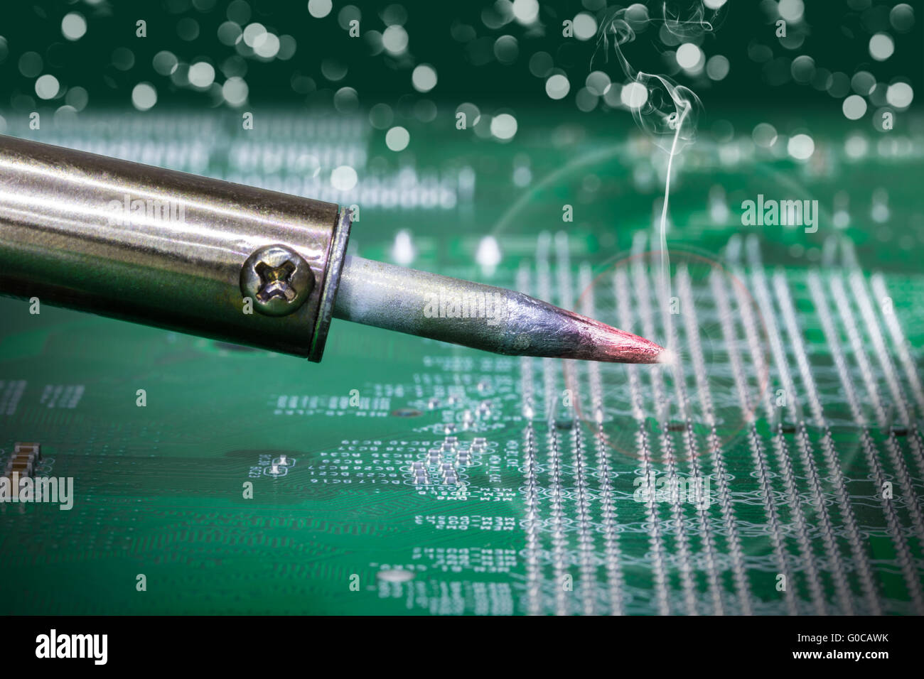 smoking soldering iron on a computer motherboard closeup Stock Photo