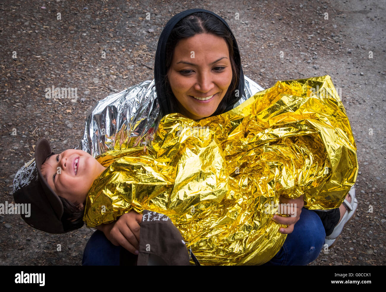 Afghani refugee mother and child wrap up in emergency blankets after getting wet crossing to Lesvos from Turkey in a raft Stock Photo
