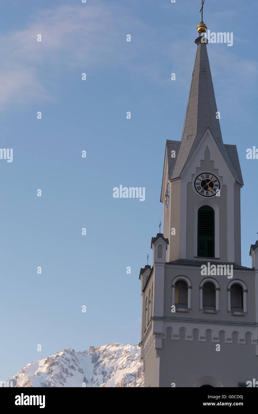 Church tower in Schladming with mountains behind Stock Photo