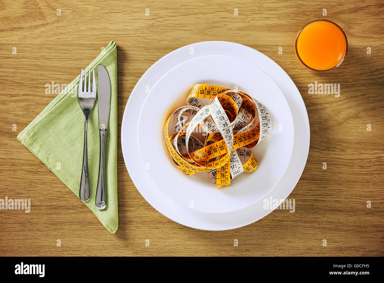 Healthy diet and weight loss concepts, table set on a wooden table with fruit juice and tape measure in a dish Stock Photo