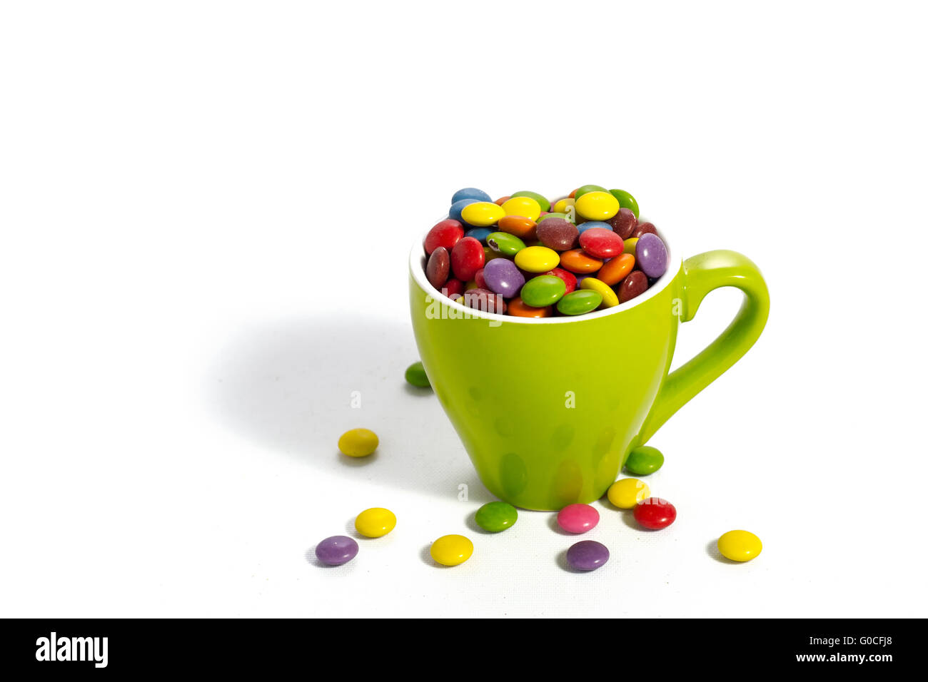 Colorful dragees in small green colored cup on white Stock Photo