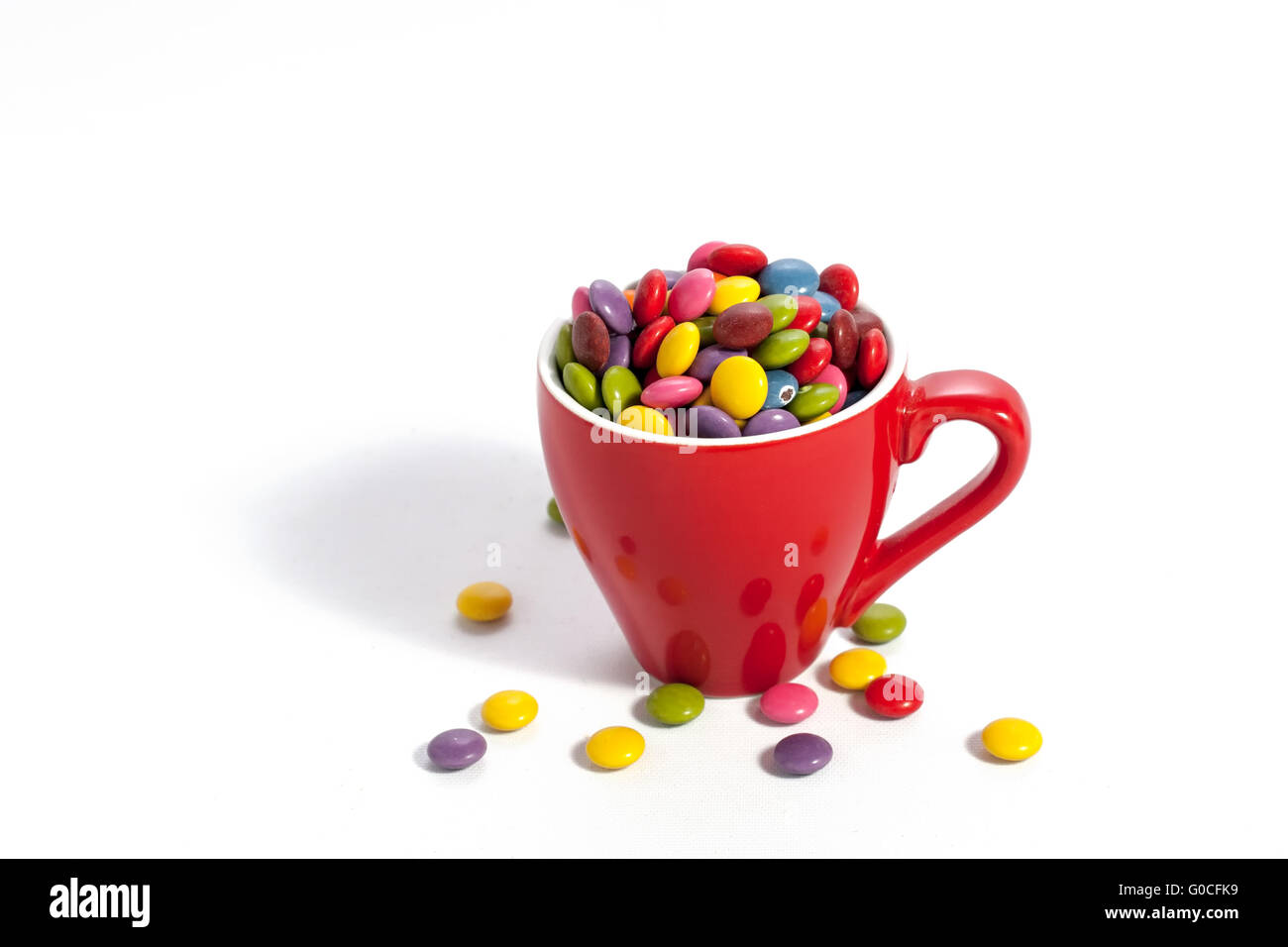 Colorful dragees in small red colored cup on white Stock Photo