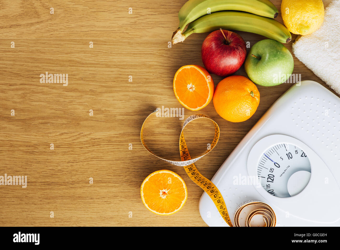 Healthy eating, fitness and weight loss concept, white scale with fruit on a wooden table, blank copy space at left Stock Photo