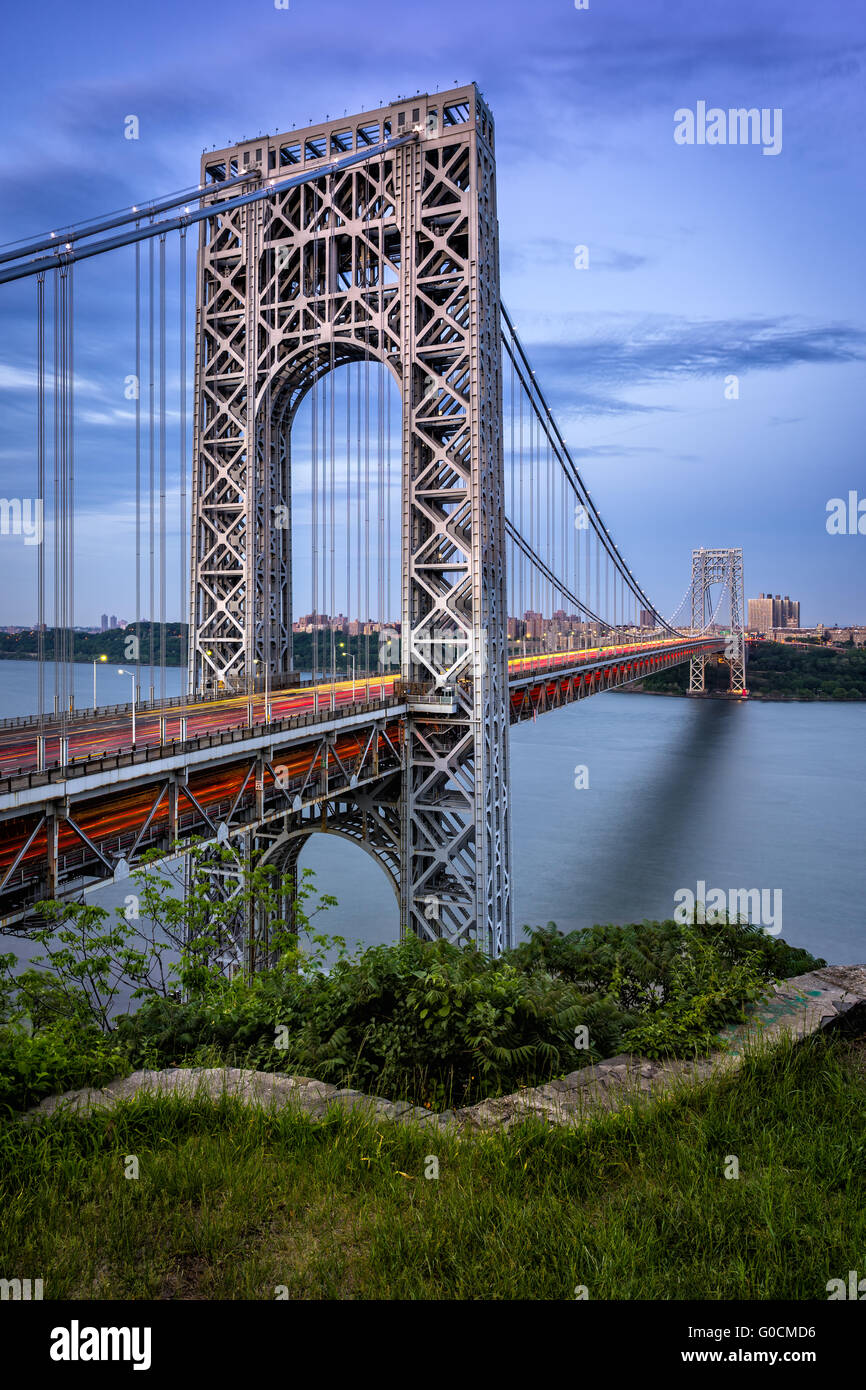 George Washington Bridge with car light trails and Hudson River at twilight. The suspension bridge links New Jersey with NYC Stock Photo